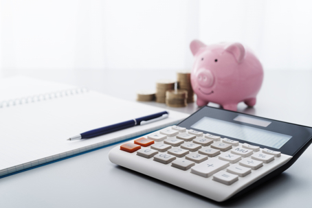 notepad, calculator, coins, and a piggy bank