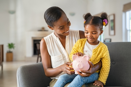 mother and daughter holding piggy bank