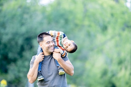 father carrying son on his shoulders